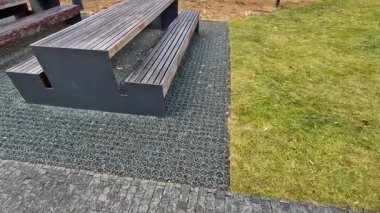 installation of a plastic mat as a substitute for lawn. plastic permeable tiles are filled with a fine putty. under the benches is a reinforced grass paving