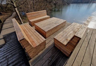 Ormanda su kenarında doğal odunlarla sıralanmış ahşap koltuklar. Güverte terası göletin yanında. Her şey kışın eklemleri olan terasta ağaç gövdesi olan tek parça.