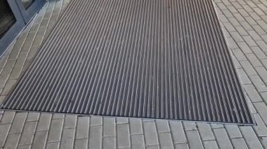 Keçeli mendil, kaset fırçası, gri alüminyum. Profiller asfalt seviyesinin altına gömülmüş. Değiştirilebilir keçeli kalemler ayakkabıları temizler ve suyu emer. Kayma riski azaldı.