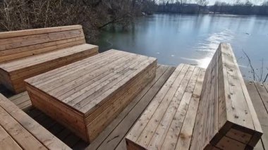 Ormanda su kenarında doğal odunlarla sıralanmış ahşap koltuklar. Güverte terası göletin yanında. Her şey kışın eklemleri olan terasta ağaç gövdesi olan tek parça.