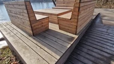 Ormanda su kenarında doğal odunlarla sıralanmış ahşap koltuklar. Güverte terası göletin yanında. Her şey kışın eklemleri olan terasta ağaç gövdesi olan tek parça.