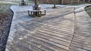 Parktaki ahşap teras. Parkta kahverengi vidalı banklar var. Zig 'i arka arkaya yerleştirmiş. Sıralar birbiri üzerine konur. Metal bir ızgaraya sabitlenmiş ağaç