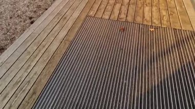 Keçeli mendil, kaset fırçası, gri alüminyum. Profiller asfalt seviyesinin altına gömülmüş. Değiştirilebilir keçeli kalemler ayakkabıları temizler ve suyu emer. Kayma riski azaldı.