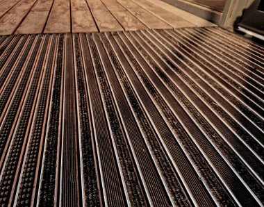 Keçeli mendil, kaset fırçası, gri alüminyum. Profiller asfalt seviyesinin altına gömülmüş. Değiştirilebilir keçeli kalemler ayakkabıları temizler ve suyu emer. Kayma riski azaldı.