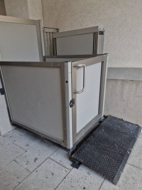 next to the stairs is a platform with a handrail for wheelchair users who cannot get over the barrier of the stairs. the elevator takes them up a level higher
