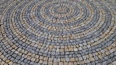 Meydanda katlanmış taşlar, gri granit kaldırımın ortasında daha büyük bir fayansla daireler çiziyor. Suyun üzerindeki daireler kaldırımın simgesidir. Büyük ve küçük harmanlanmış.