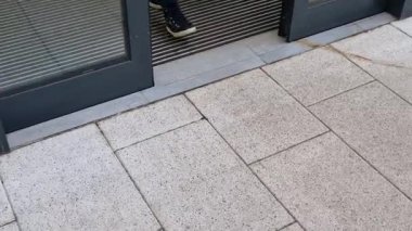 Binanın girişindeki endüstriyel paspas temizleme bölgeleri. Kemer ya da yarım daire şeklinde siyah plastik bir minder kireçtaşı mozaik fayansların üzerinde yatar.