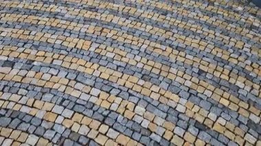 Meydanda katlanmış taşlar, gri granit kaldırımın ortasında daha büyük bir fayansla daireler çiziyor. Suyun üzerindeki daireler kaldırımın simgesidir. Büyük ve küçük harmanlanmış.