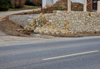 İki arsa arasında eski taş duvar yeniden inşa ediliyor. Taşlar sökülmüş ve çimento harcına yapıştırılmış. Taş ustası parkta bir duvar inşa ediyor. Eklemler ve çalılar onarıldı.