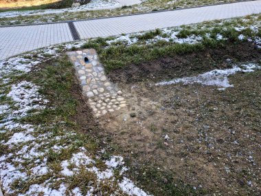 Taş duvar panelleri ve gabion duvarları olan drenaj göleti. Yağmur sırasında su yavaşlar ve kanalizasyon borusundan kanalizasyona taşar. Yeni tamamlanmış gözyaşları