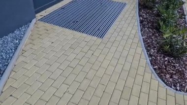 Keçeli mendil, kaset fırçası, gri alüminyum. Profiller asfalt seviyesinin altına gömülmüş. Değiştirilebilir keçeli kalemler ayakkabıları temizler ve suyu emer. Kayma riski azaldı.