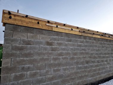 Çelik ve betonla doldurulmuş beton bloklardan beton bir duvar inşa etmek. Bir ev ya da çit, köpük, plastik üzerine içi boş tuğlalardan oluşan gri bir duvar.