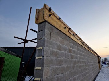 Çelik ve betonla doldurulmuş beton bloklardan beton bir duvar inşa etmek. Bir ev ya da çit, köpük, plastik üzerine içi boş tuğlalardan oluşan gri bir duvar.