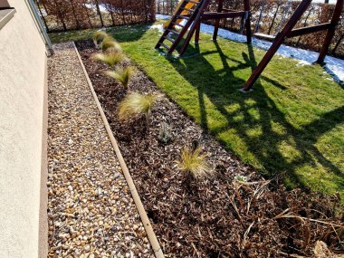 Süslü otlarla dolu çiçek tarhı sonbahar güneşinde kuru yapraklar sarı yaprak demetleri parlar. Arka plandaki çalılıklarda ve boynuz direğinin yaşam alanında. Kahverengi yapraklar çimenlik, kaldırım taşı, kumtaşı