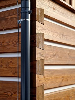 Ahşap kulübe. beyaz çizgili ve pencereli kirişler. Dalgalar halinde oyulmuş süsler. Düğümler kahverengi bir lekeyle işaretlenmiş. kirişler yapı taşları gibi birbirine uyuyor.