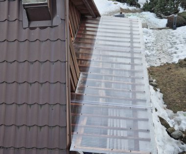 Ahşap pergola ve pleksiglass çatılı teras. Sarmaşıklar geriliyor, kirişlerin altında sürünüyorlar. Bahçe ya da park. Alkolsüz duvar şarabı bölgesinde oturuyor. Kırsal restoran Fransa, kiriş, küre, lamba