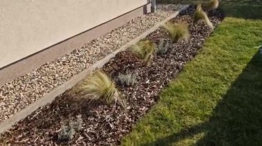 Süslü otlarla dolu çiçek tarhı sonbahar güneşinde kuru yapraklar sarı yaprak demetleri parlar. Arka plandaki çalılıklarda ve boynuz direğinin yaşam alanında. Kahverengi yapraklar çimenlik, kaldırım taşı, kumtaşı