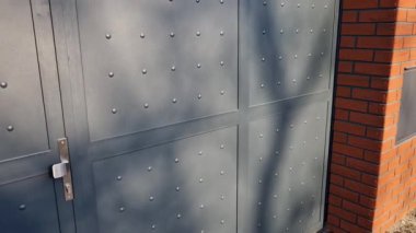 Galvanizli konut kapısı, perçinlenmiş metal levha, şebeke kare şeklinde. Gümüş endüstriyel kapı, karanlık.