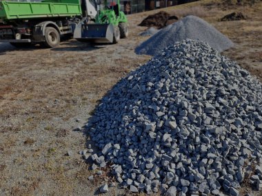 İnşaat malzemelerin taşınması ve taşınmasına bağlıdır. Park inşaatı için el çöplüğü. Park inşaatı sırasında yükleyici ve konteyner kamyonu. Büyük granit yığınları, yükleyici