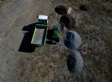 İnşaat malzemelerin taşınması ve taşınmasına bağlıdır. Park inşaatı için el çöplüğü. Park inşaatı sırasında yükleyici ve konteyner kamyonu. Büyük granit yığınları, yükleyici