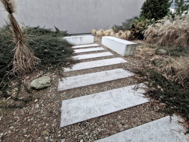 Bahçedeki düz taşlar, taş çakıl taşlarıyla kaplanmış yataklı bir patika oluşturuyor. İki sıra halinde basamaklar, ziyaretçileri parka götürüyor, dinlenme bölgesi, kuru bölge.