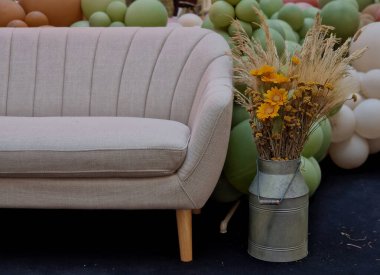 Elinde Janlky olan önlüklü bir adam. Samandan yapılmış çiftçi kuklası. Tavukların oturduğu balyalar ve arka planda şişme plastik balyalar. Çiçekçi bahar ve balo kutlamalarına hazırlanıyor.