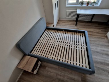 Kafesli kafes çerçevesi doğal bir ahşap renk ölçme, yatak ızgarası, çatalsız, lükslü gri çift kişilik yatak. Şilteler daha gelmedi. Ahşap kaplama döşeme ve kumaş kaplama.