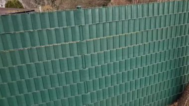 Tel örgülerin arasından plastik şeritler dokuyordu. Çevredeki yayalara karşı koruma