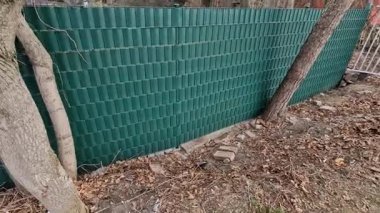 Tel örgülerin arasından plastik şeritler dokuyordu. Çevredeki yayalara karşı koruma