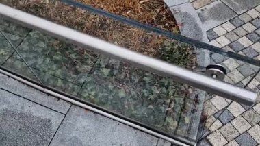 Cam, camı delmek için tasarlanmış vida ve çamaşır makineleriyle duvara tutturulmuş. Kaplama bir tırabzan ve hava bölümüdür. İstasyon, sokak, lüks.