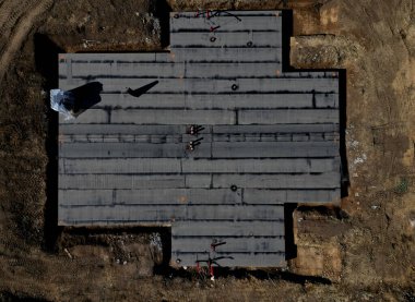 Yan yana yapılmış siyah asfalt karton rulo. Çatı ve ev yalıtıcıları için depo. Temiz bir giriş için propan gazı ile kaynak yapıyorlar.