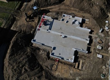 Beton bir temel levhası. Tuğla ustaları üstüne tuğla bloklar inşa eder ve bir zemin inşa ederler. Beton kaplamalı muşambalarla kaplı. Beton bir pompa karışımından beton döküyor.