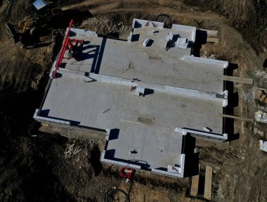 Beton bir temel levhası. Tuğla ustaları üstüne tuğla bloklar inşa eder ve bir zemin inşa ederler. Beton kaplamalı muşambalarla kaplı. Beton bir pompa karışımından beton döküyor.