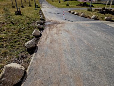 Park yerlerinden korunmak için şeritler arasında gri taşlar var. Taşımacılık çözümleri şehir yolu ve bisiklet yolunun yanındaki otoparkta. Asfalt yüzeyler ve çimenler, metal direkleri kilitleyin. kırmızı çizgiler
