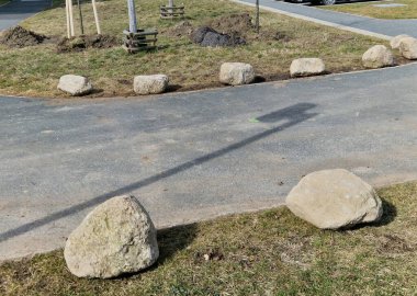 Park yerlerinden korunmak için şeritler arasında gri taşlar var. Taşımacılık çözümleri şehir yolu ve bisiklet yolunun yanındaki otoparkta. Asfalt yüzeyler ve çimenler, metal direkleri kilitleyin. kırmızı çizgiler