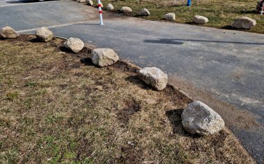 Park yerlerinden korunmak için şeritler arasında gri taşlar var. Taşımacılık çözümleri şehir yolu ve bisiklet yolunun yanındaki otoparkta. Asfalt yüzeyler ve çimenler, metal direkleri kilitleyin. kırmızı çizgiler