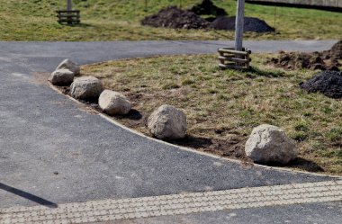 Park yerlerinden korunmak için şeritler arasında gri taşlar var. Taşımacılık çözümleri şehir yolu ve bisiklet yolunun yanındaki otoparkta. Asfalt yüzeyler ve çimenler, metal direkleri kilitleyin. kırmızı çizgiler