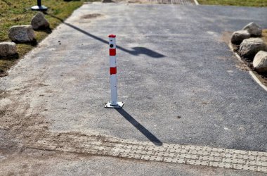 Park yerlerinden korunmak için şeritler arasında gri taşlar var. Taşımacılık çözümleri şehir yolu ve bisiklet yolunun yanındaki otoparkta. Asfalt yüzeyler ve çimenler, metal direkleri kilitleyin. kırmızı çizgiler