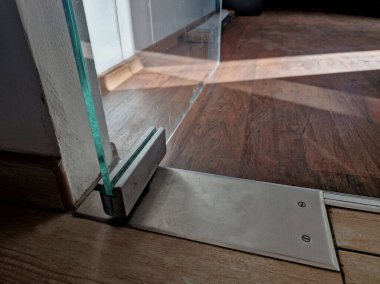 Modern bir mağazanın duvarları ve kapıları camdan yapılmış butikler. Menteşeler bir menteşeyle tutunur. Çerçevesiz. Daha aydınlık ve ferah, pankart var. İçerde, içeride.