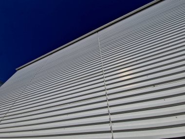 Ön cephesinde metal levha olan metal bir garaj. Dik yatay şeritli lojistik salonu. Dayanıklı ve bakımsız yüzeyler fabrika deposu, otomobil endüstrisi