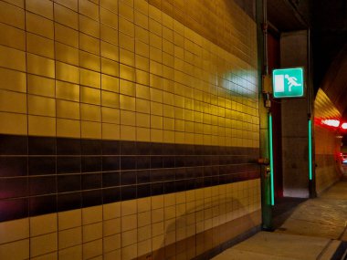 Tünelden çıkan acil durum çıkışını işaret ediyor. Oklar ve tünelin yan koridorunun girişinin daha yakın olduğu mesafe kullanılıyor. metrik birimlerde navigasyon. Yangın kapılarının LED ışıklandırması