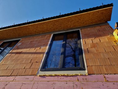 brick house with three windows and a good view of the countryside. replica of a historic cottage. bricks made from recycled ash and plaster. landscape