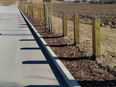 Tahta kirişlerden yapılmış kalın çizgiler. Araç girişine karşı önlem alan doğal park. Bollardın tepesinde metal bir çatı vardır.