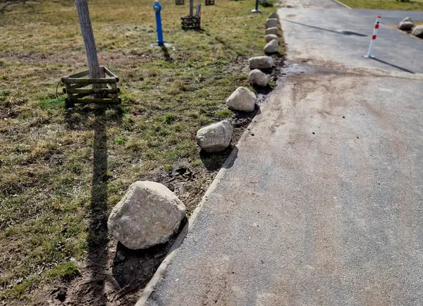 Park yerlerinden korunmak için şeritler arasında gri taşlar var. Taşımacılık çözümleri şehir yolu ve bisiklet yolunun yanındaki otoparkta. Asfalt yüzeyler ve çimenler, metal direkleri kilitleyin. kırmızı çizgiler