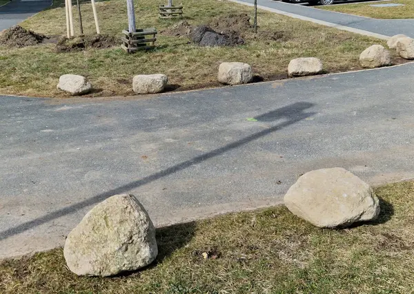 Park yerlerinden korunmak için şeritler arasında gri taşlar var. Taşımacılık çözümleri şehir yolu ve bisiklet yolunun yanındaki otoparkta. Asfalt yüzeyler ve çimenler, metal direkleri kilitleyin. kırmızı çizgiler