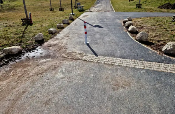 Park yerlerinden korunmak için şeritler arasında gri taşlar var. Taşımacılık çözümleri şehir yolu ve bisiklet yolunun yanındaki otoparkta. Asfalt yüzeyler ve çimenler, metal direkleri kilitleyin. kırmızı çizgiler