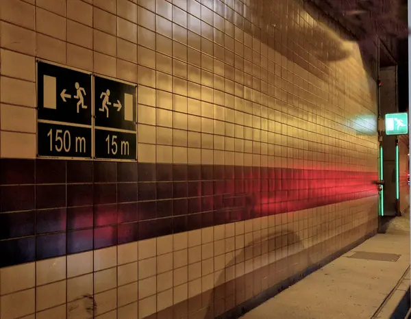Tünelden çıkan acil durum çıkışını işaret ediyor. Oklar ve tünelin yan koridorunun girişinin daha yakın olduğu mesafe kullanılıyor. metrik birimlerde navigasyon. Yangın kapılarının LED ışıklandırması