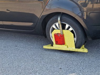 Araba yanlış park edilmiş ve sürücü polisten para cezası ve tekerlek kilidi almış. Ceza ödendikten sonra tekerlek kelepçesi polis tarafından açılacak..
