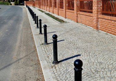 Kara metal kalınlar yaya bölgesindeki yayaları ya da gezinti alanındaki parktaki yayaları korumak için kullanılır. Gri sütunlar kaldırımdaki araçların park edilmesini engelliyor, çiçek tarhı, resmi şeritler