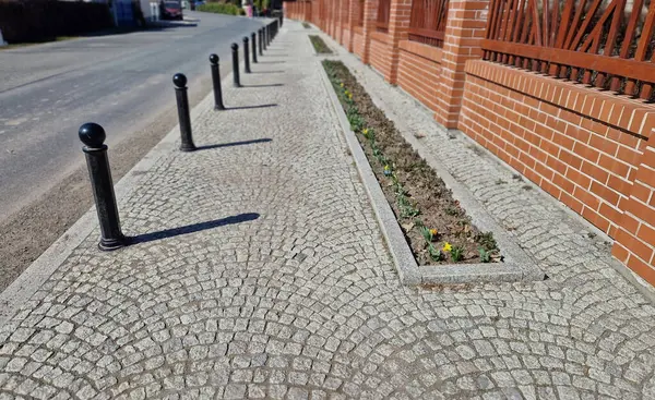 Kara metal kalınlar yaya bölgesindeki yayaları ya da gezinti alanındaki parktaki yayaları korumak için kullanılır. Gri sütunlar kaldırımdaki araçların park edilmesini engelliyor, çiçek tarhı, resmi şeritler